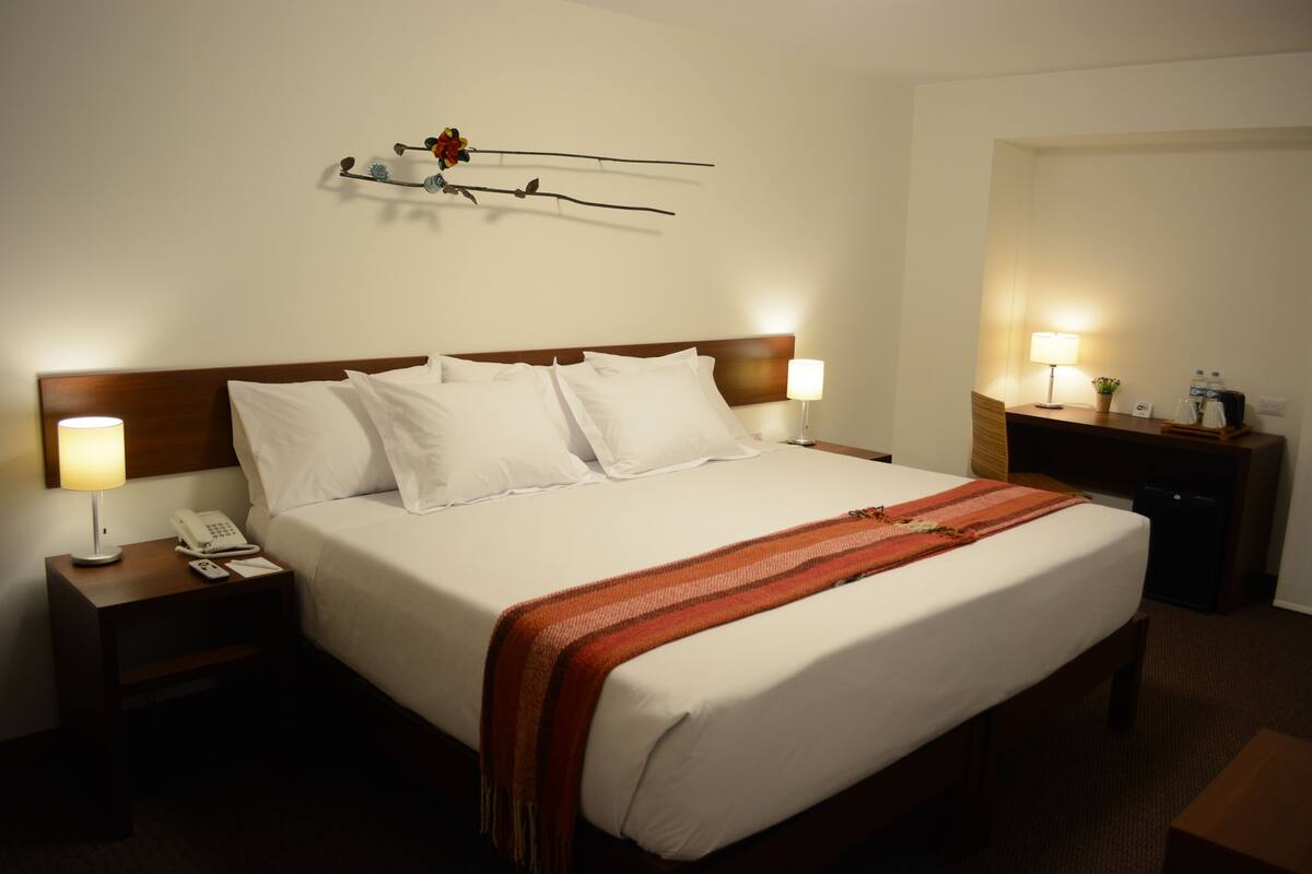 Une chambre d’hôtel comprenant un lit, des lampes de chevet, un téléphone, une table de chevet et un élément décoratif mural.