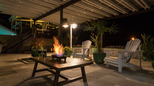 An outdoor patio area with a fire feature, two Adirondack chairs, and a table. - Hotel Parque das Flores (Campos do Jordão)