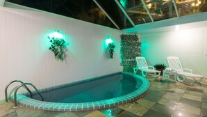 A swimming pool with a tiled edge, a glass ceiling, and two wall-mounted lights. - Hotel Parque das Flores (Campos do Jordão)