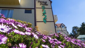 A building with a sign reading "Parque das Flores" and a decorative green design. - Hotel Parque das Flores (Campos do Jordão)
