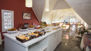 A buffet setup with various food items and a large window in the background. - Hotel Parque das Flores (Campos do Jordão)