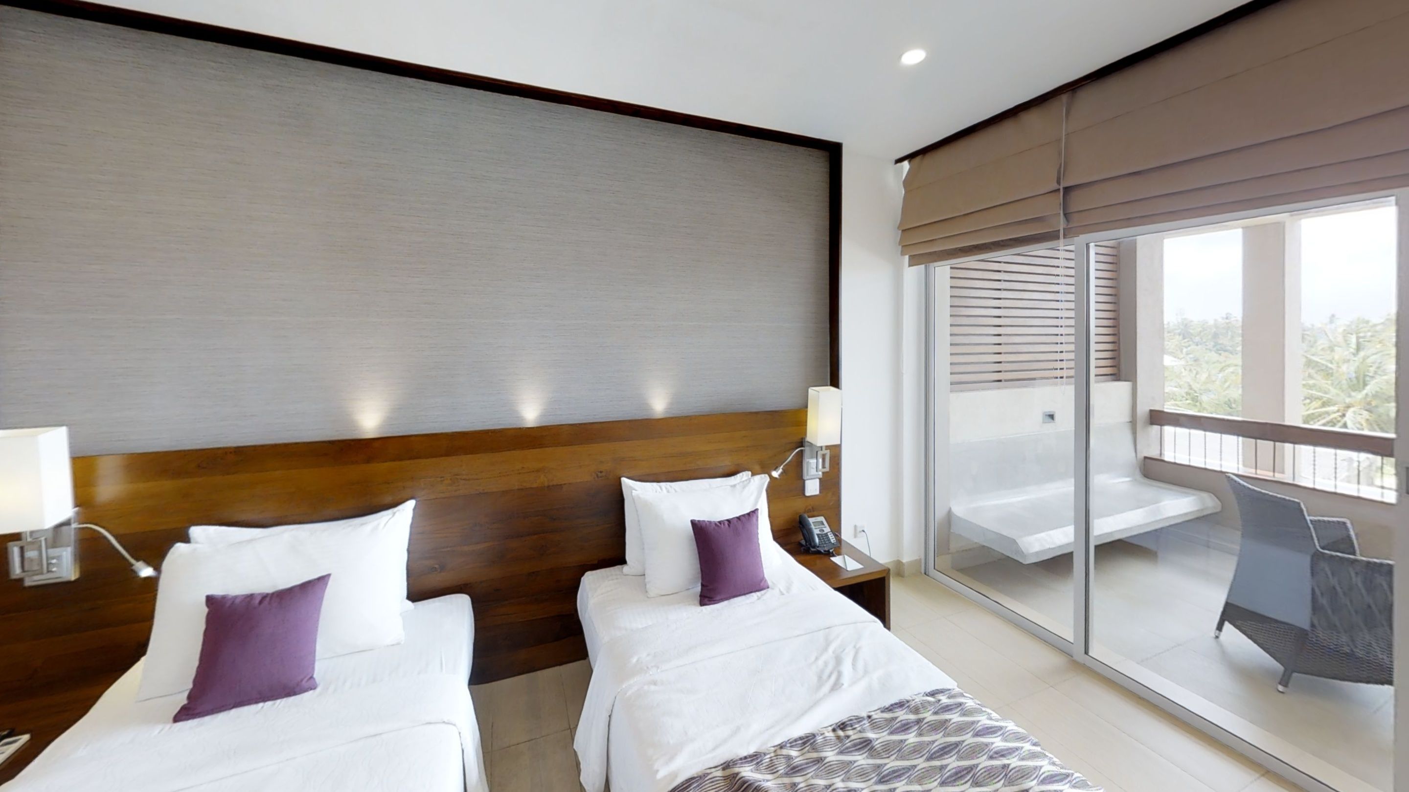 Ein Hotelzimmer mit zwei Betten, einem großen Fenster und einem Balkon sowie einem hölzernen Kopfteil.