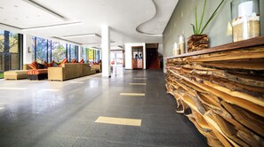 Un vestíbulo espacioso con un diseño moderno, que incluye una recepción, zona de estar y ventanas amplias.