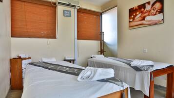 Two beds with crisp linens and a neatly folded towel, complemented by a wooden headboard and table.