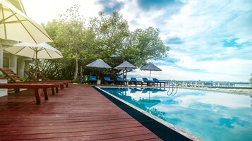 Una piscina al aire libre, sombrillas, sillones reclinables de piscina