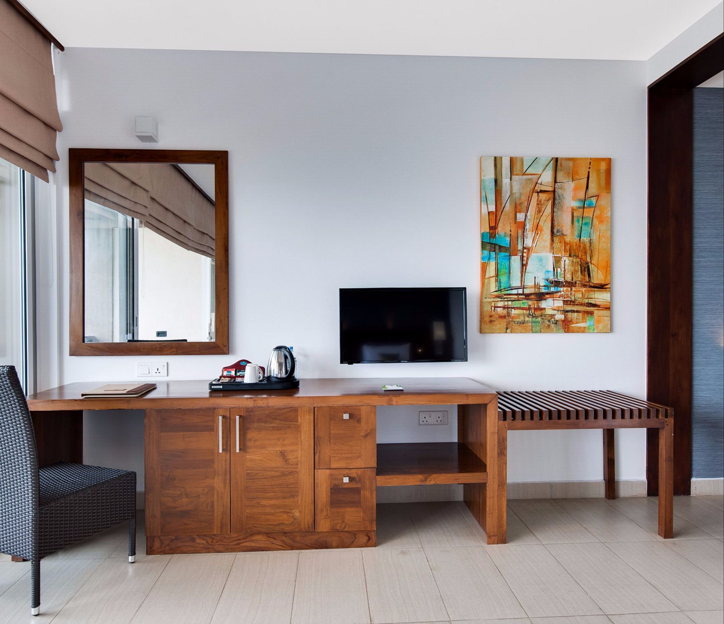 A modern room with a wooden desk, a chair, a TV, and a painting.
