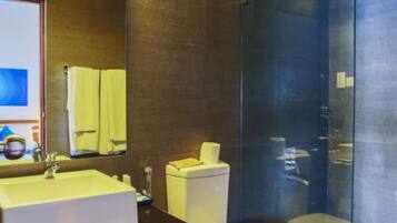A modern bathroom with a large mirror, a sink, a toilet, and a glass-enclosed shower area.