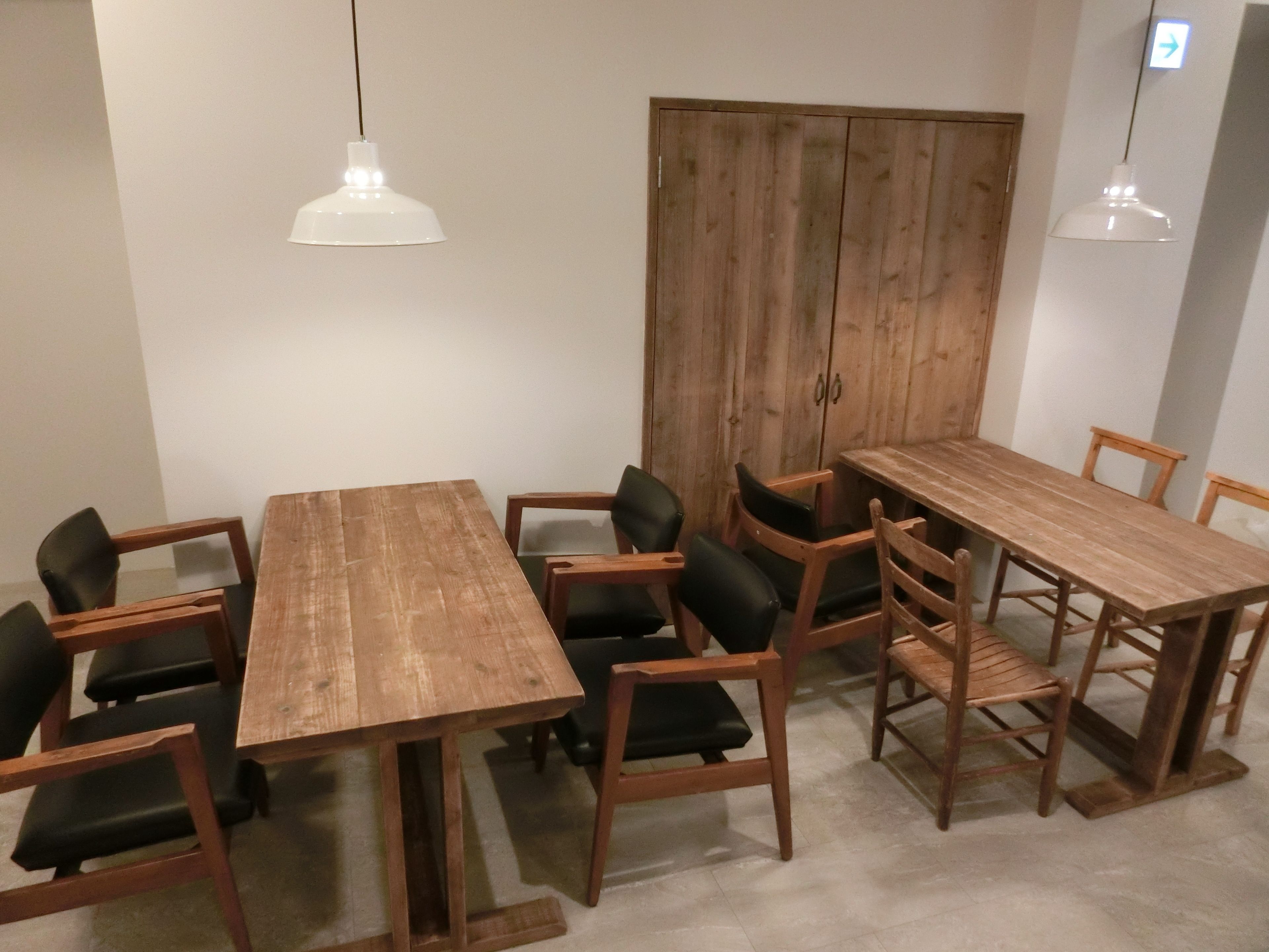 A dining area with a wooden table and chairs, two pendant lights, and a wooden cabinet.