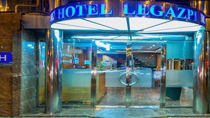 La entrada del Hotel Legazpi, con puerta de cristal y estructura metálica.