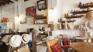 A rustic interior with wooden furniture, a variety of hats and bags displayed on shelves, and a wooden table. - Gotum Hostel & Restaurant (Phuket)