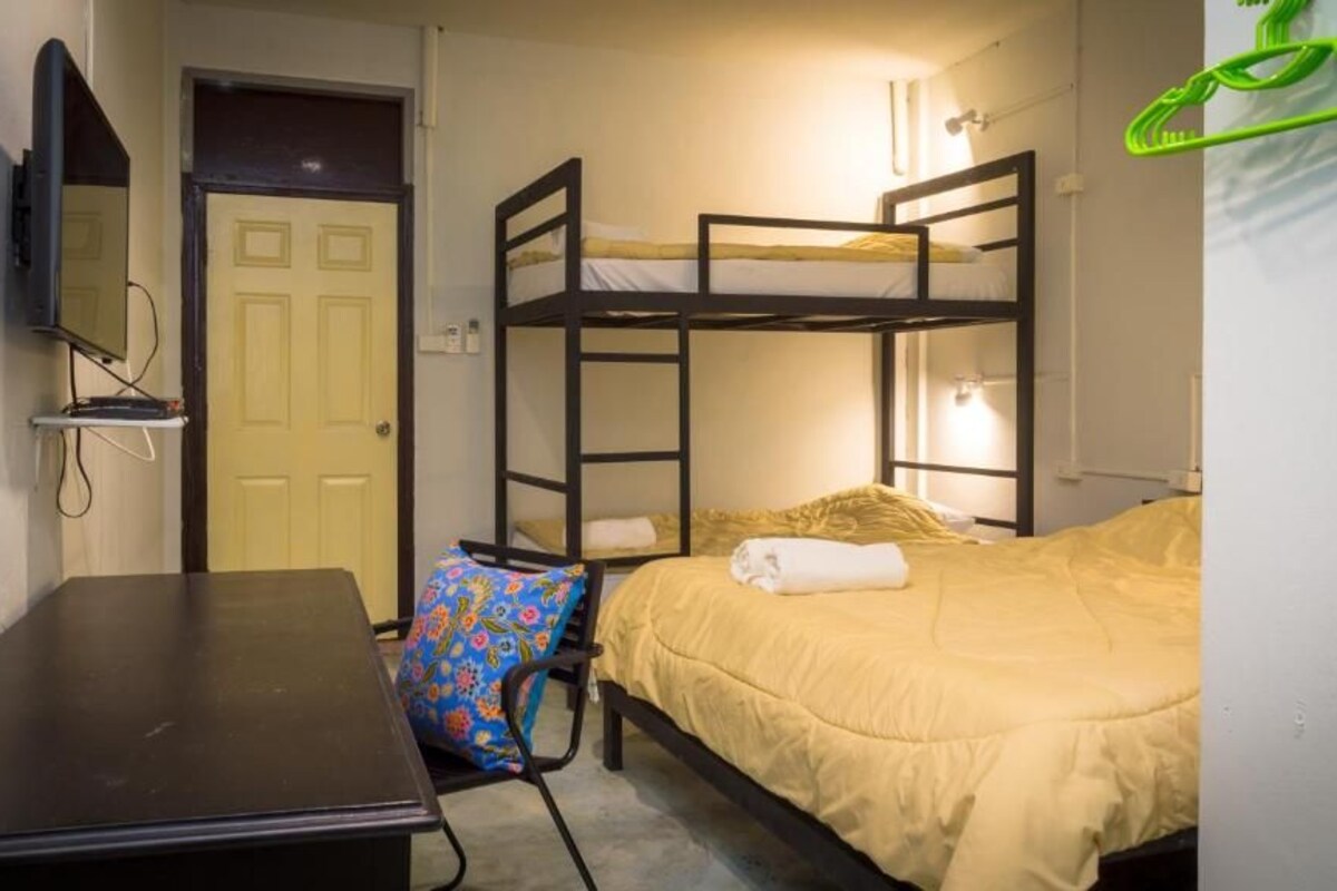 A bunk bed room with a desk, a chair, and a television on the wall.