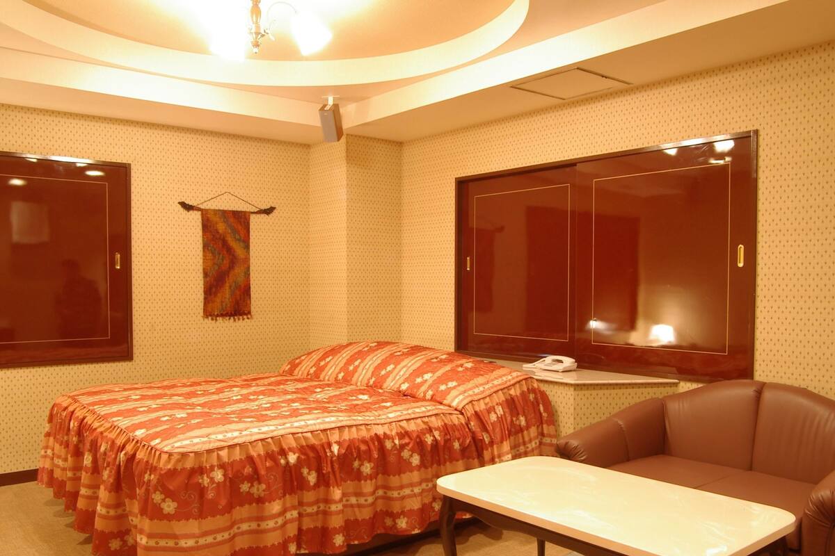 Una habitación de hotel con una cama, un escritorio, una silla y un armario.