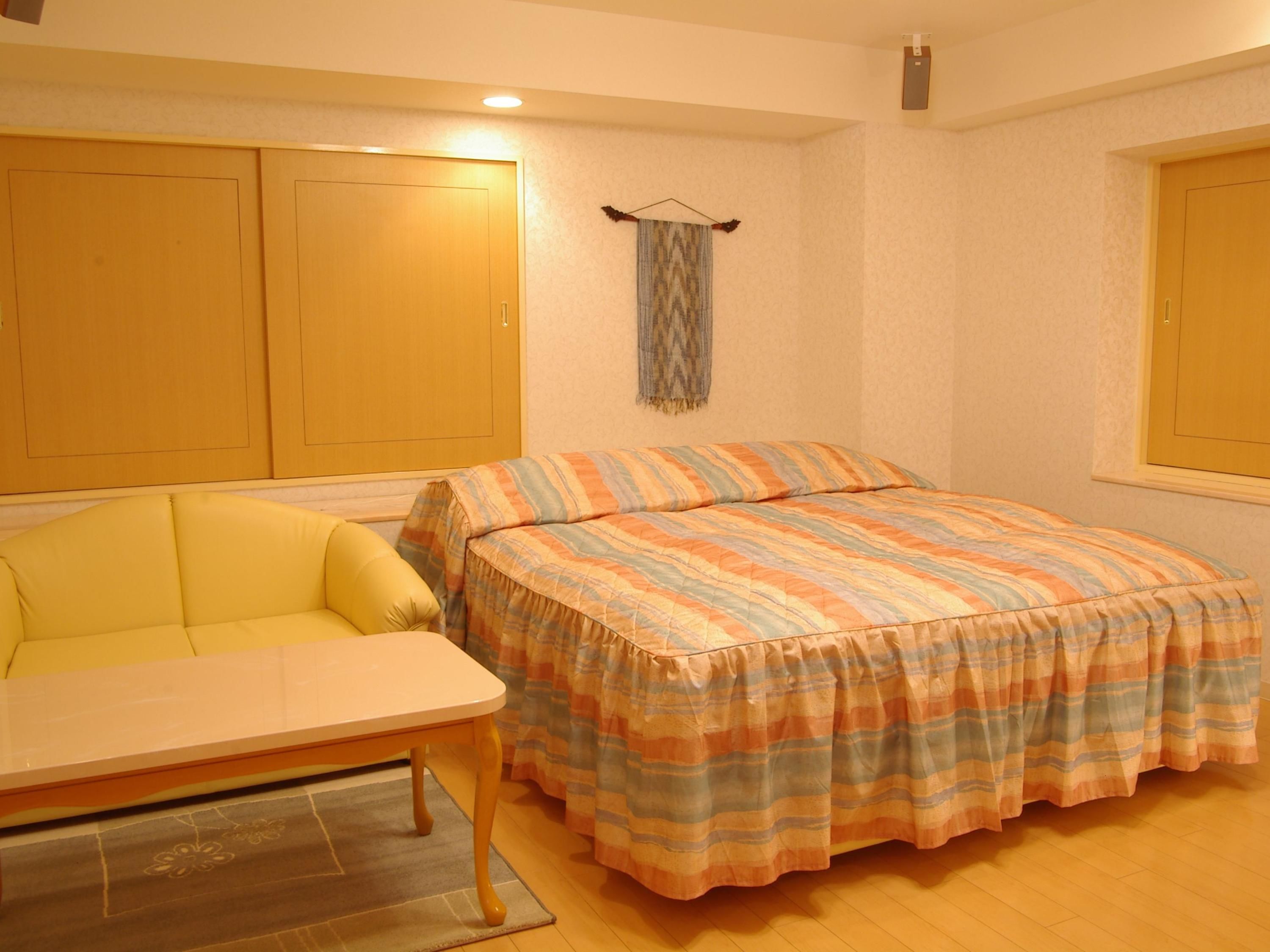 A bedroom with a bed, a sofa, and a desk.