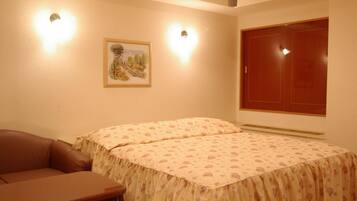 A bedroom with a bed, a chair, a wardrobe, and a framed picture on the wall.