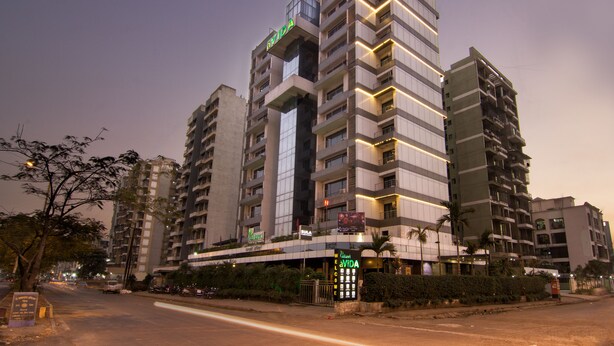 Un hôtel à plusieurs étages, doté d’une architecture moderne, avec des balcons et une entrée imposante agrémentée d’une enseigne.