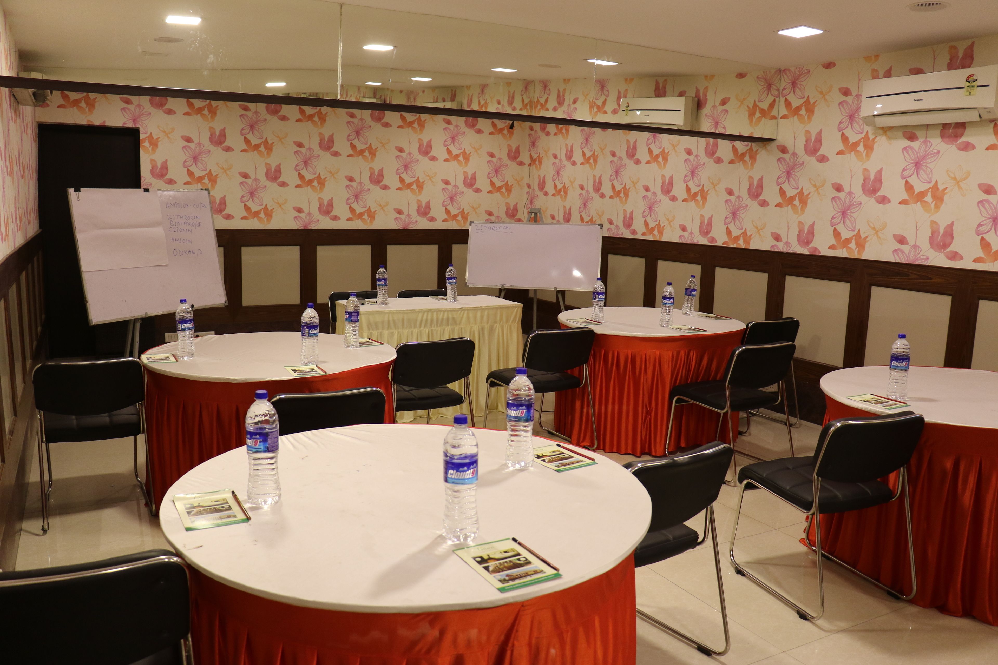 A conference room with round tables, chairs, and whiteboards.