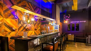 Un espace bar avec un mur en bois, des tabourets de bar et un panneau lumineux au néon.