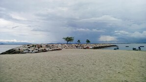 A sandy beach with a rocky breakwater and a few trees. - 8 Boutique By The Sea (George Town)