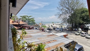 A view of a parking area with cars and a building with a traditional roof. - 8 Boutique By The Sea (George Town)