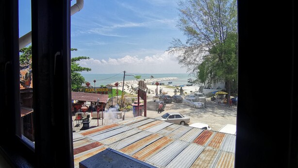 A view from inside a building looking out to a beach area with a sign for 'Pearl Garden'. - 8 Boutique By The Sea (George Town)