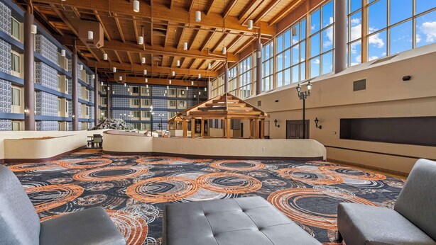 A spacious lobby with a high ceiling, large windows, and a patterned carpet. - Red Lion Hotel Charlotte (Charlotte)