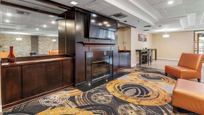 A hotel lobby with a reception desk, a fireplace, a television, and seating area. - Red Lion Hotel Charlotte (Charlotte)