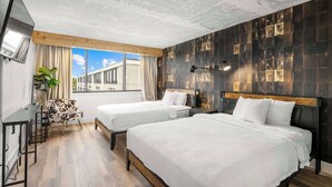 A hotel room with two beds, a desk, a chair, and a large window offering a city view. - Red Lion Hotel Charlotte (Charlotte)