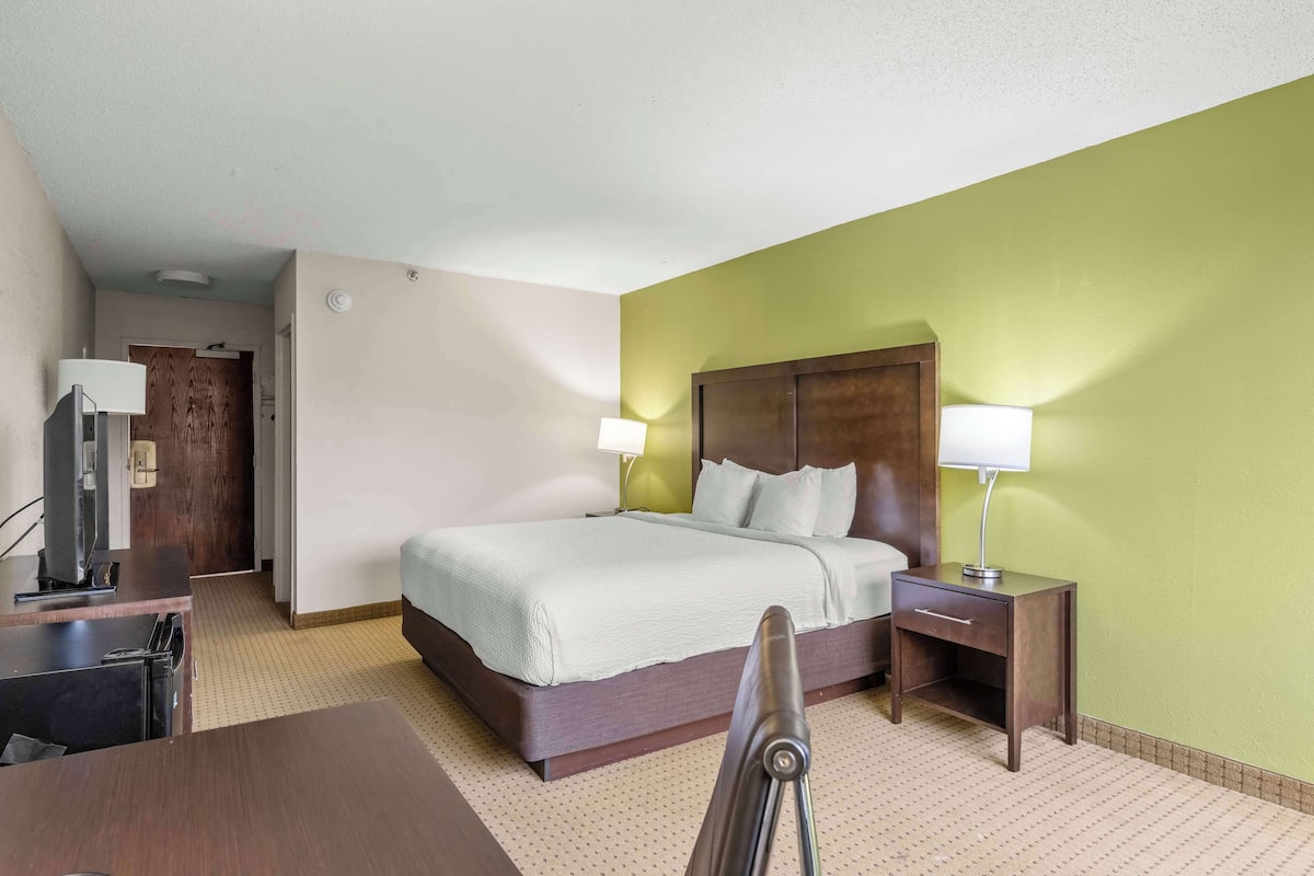 A hotel room with a bed, bedside tables, a desk, and a chair.