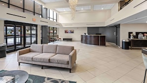 A spacious lobby with a sofa, a reception desk, and a chandelier. - Red Lion Hotel Charlotte (Charlotte)