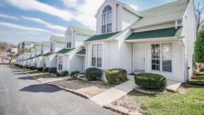 A row of identical white single-story houses with green roofs and small front yards. - The Townhouses (Branson)