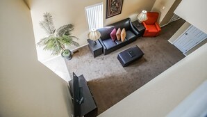 A living room with a sofa, armchairs, a coffee table, a TV, and a potted plant. - The Townhouses (Branson)