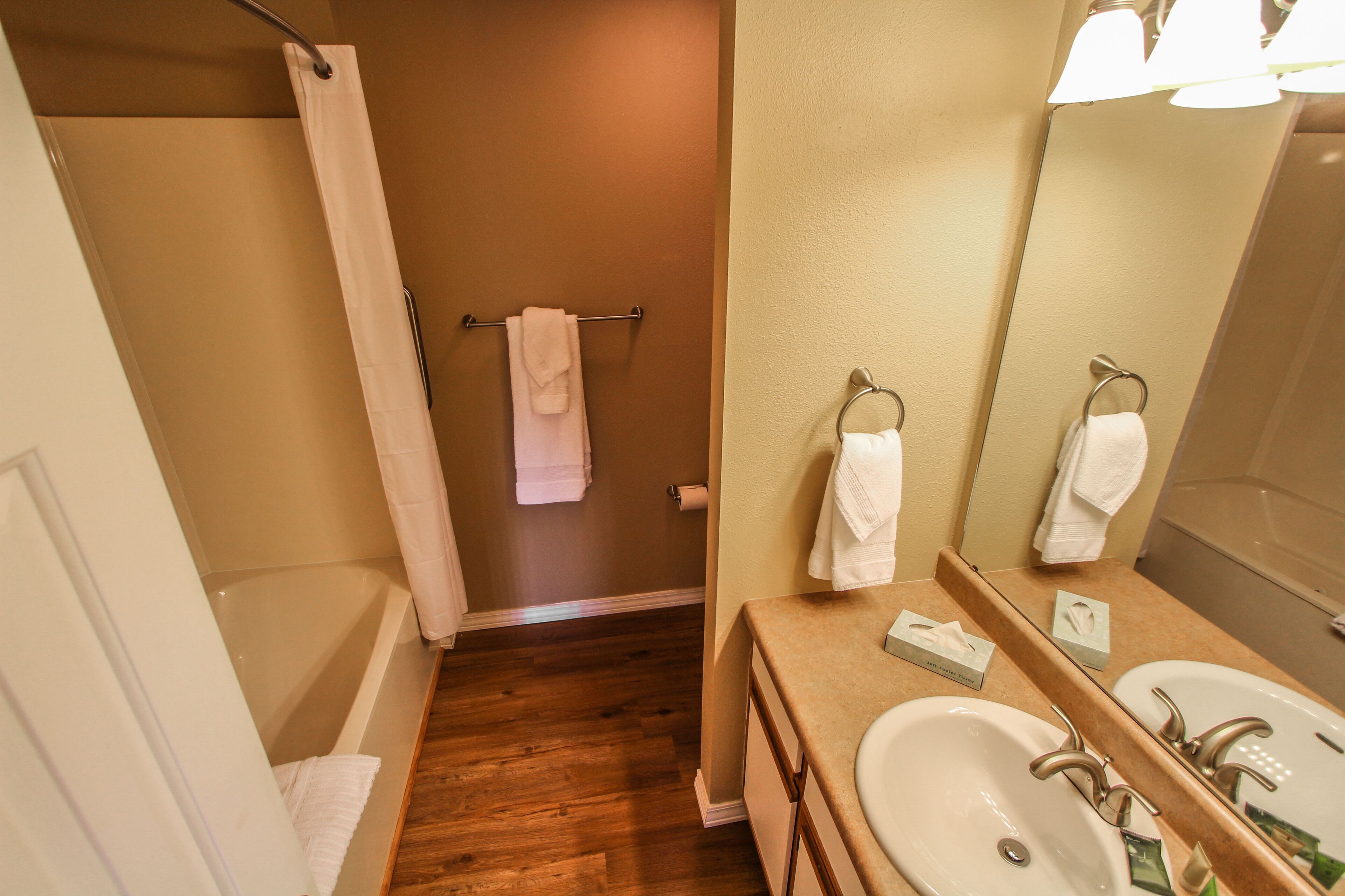 A bathroom with a bathtub, two sinks, a mirror, and a towel rack.