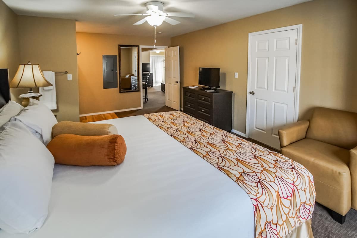 Une chambre d’hôtel avec un grand lit, un bureau, une chaise, une télévision et une armoire.