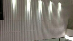Una habitación moderna con paneles verticales y una pared divisoria de vidrio.