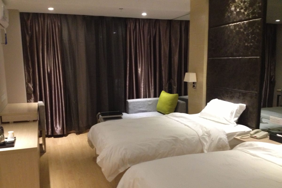 Habitación de hotel con dos camas, un escritorio, una silla, una lámpara y un teléfono en la mesita de noche.