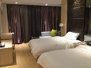 Ein Hotelzimmer mit zwei Betten, einem Schreibtisch, einem Stuhl, einer Lampe und einem Telefon auf dem Nachttisch.