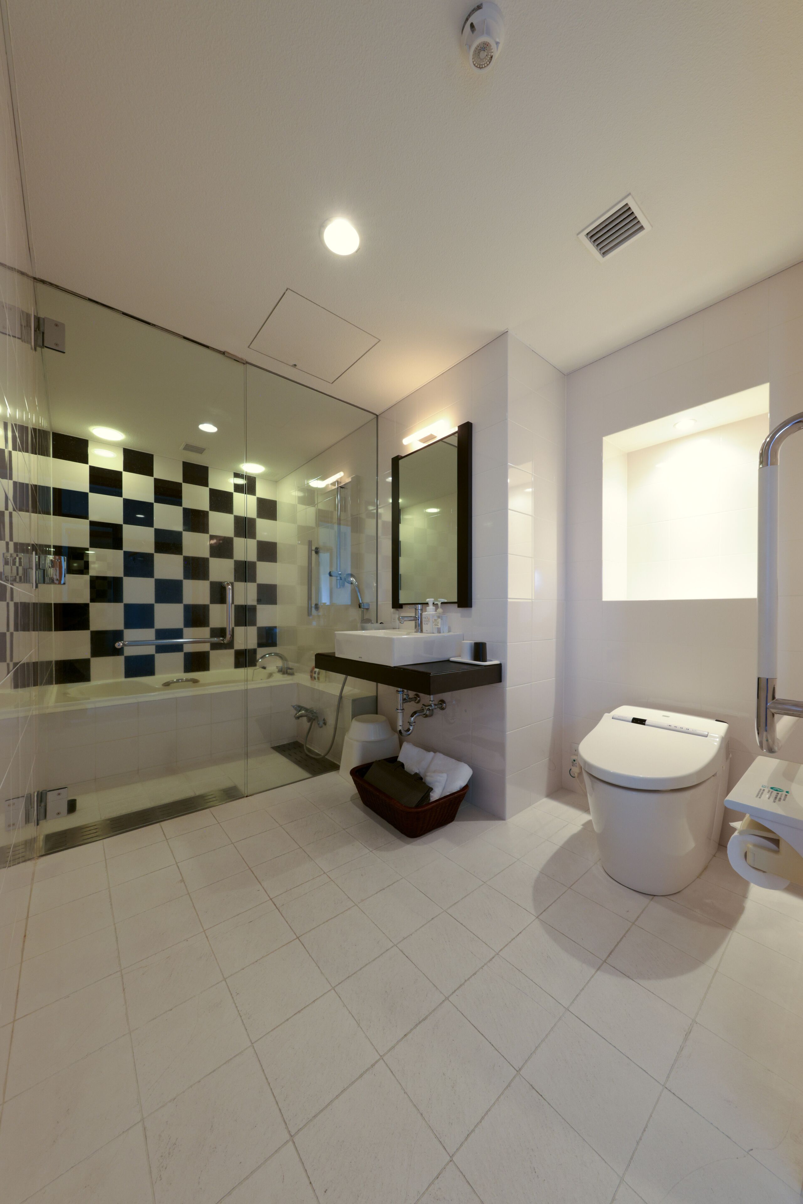 A modern bathroom with a glass shower enclosure, a white toilet, and a sink with a mirror above.