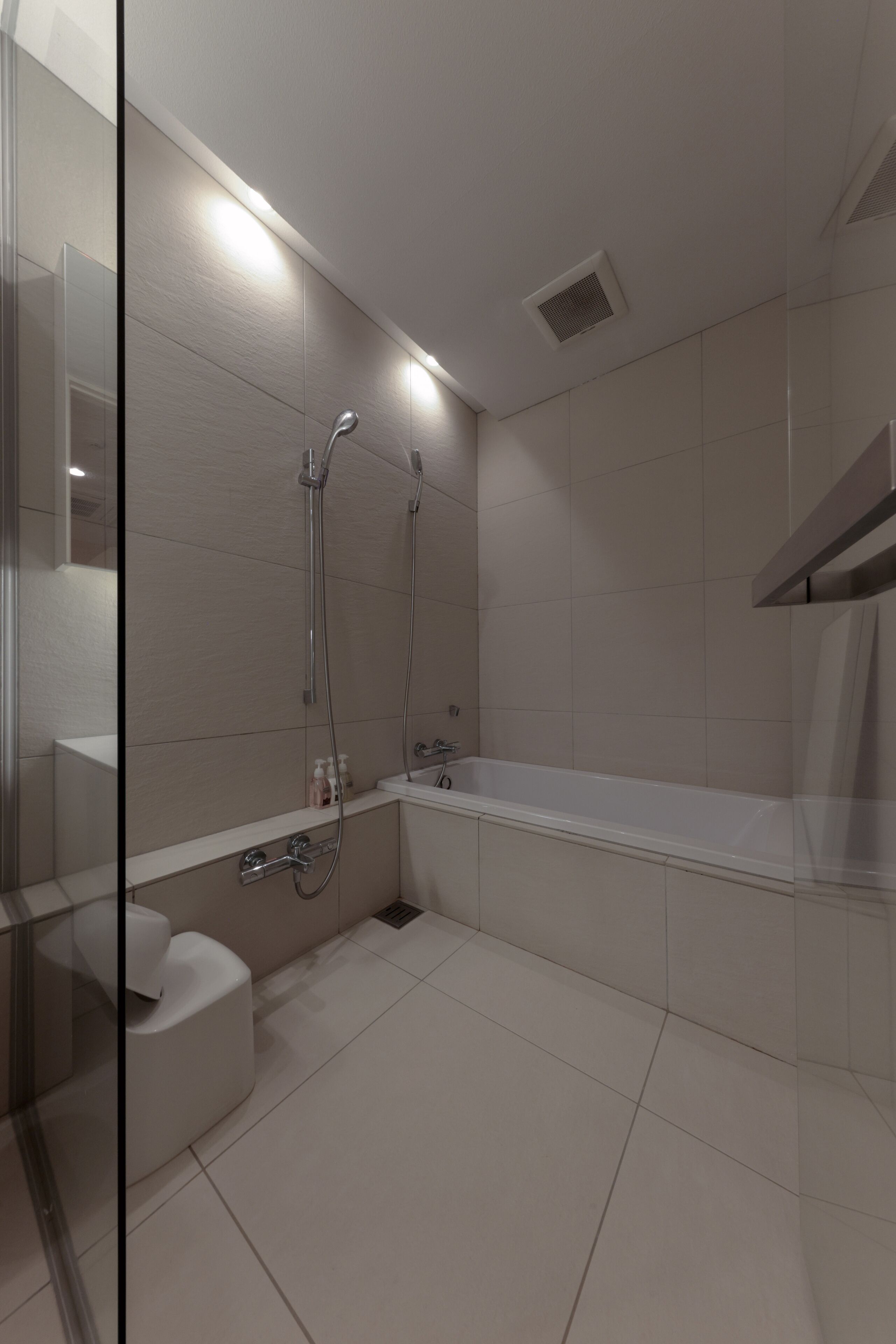 A modern bathroom with a glass shower enclosure, a white bathtub, and a toilet.
