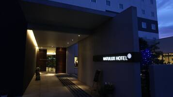 Exterior de um hotel com design moderno, destacando uma placa grande com a inscrição 'NATULUX HOTEL'.