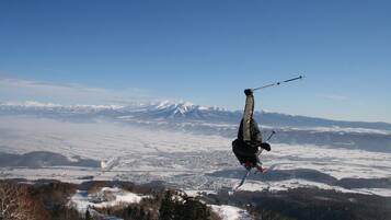A person skiing on a snowy slope with a clear view of a mountain range and a town in the distance.