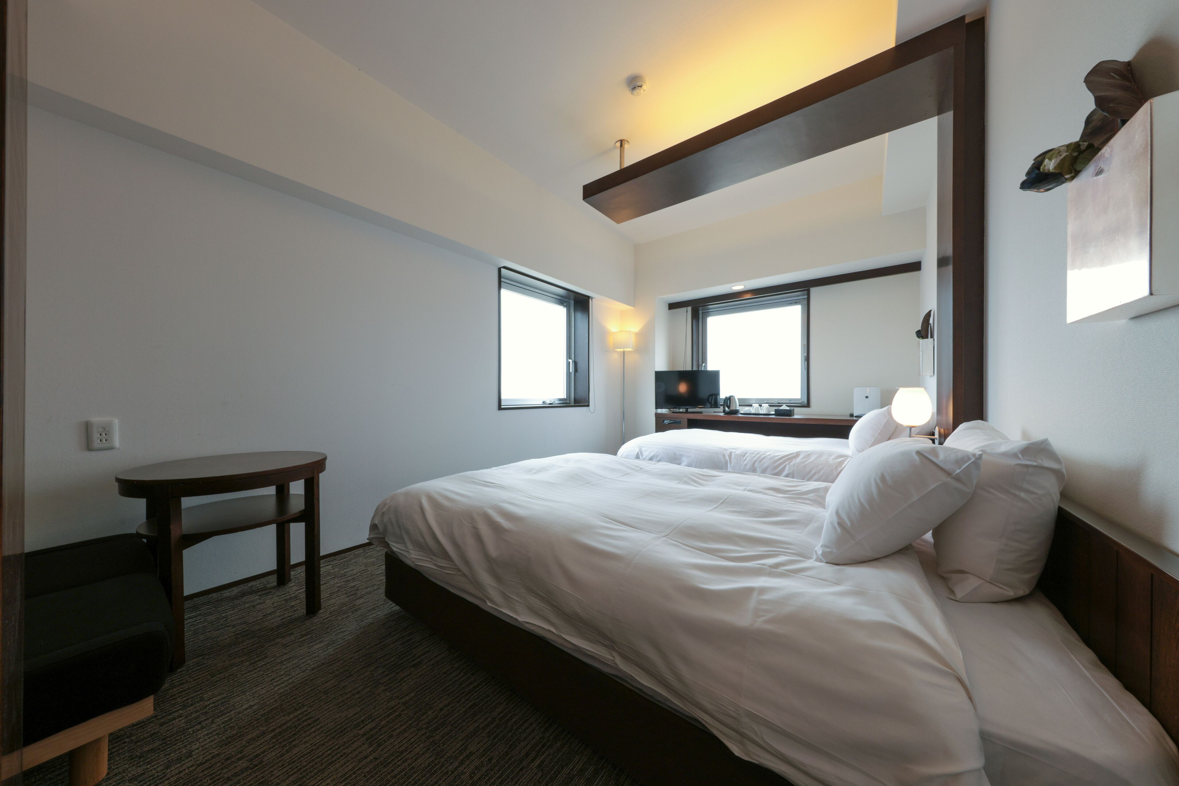 Ein Hotelzimmer mit einem großen Bett, einem Schreibtisch, einem Stuhl, einem Fenster und einem Spiegel.