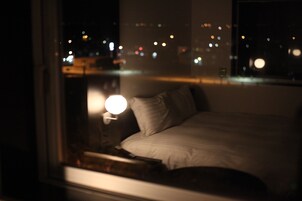 A dimly lit hotel room with a bed and a nightstand.