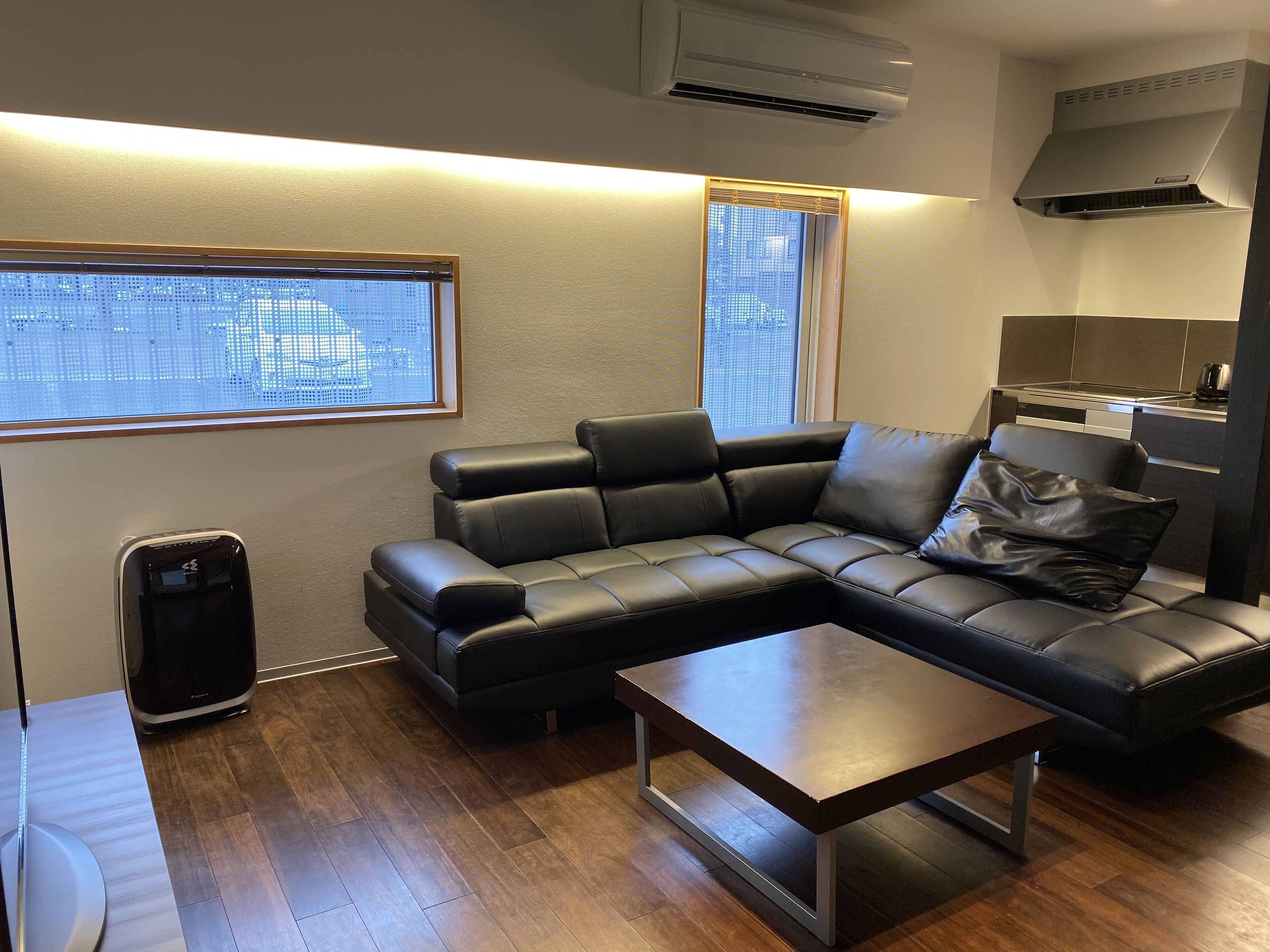 Una sala de estar moderna con un sofá seccional, una mesa de centro y una cocina integrada.