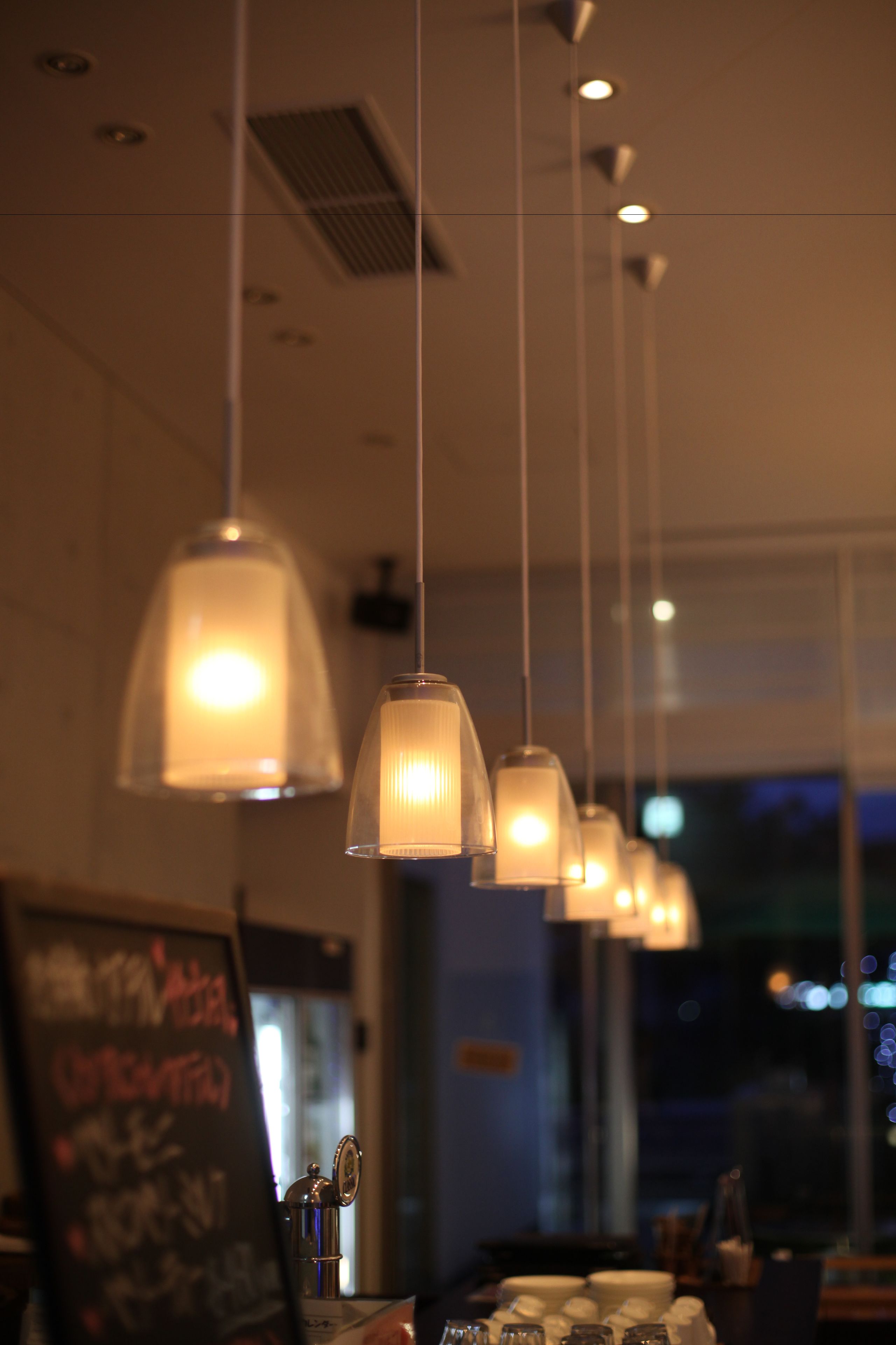 A restaurant interior with pendant lighting, a chalkboard menu, and a view of the outside.