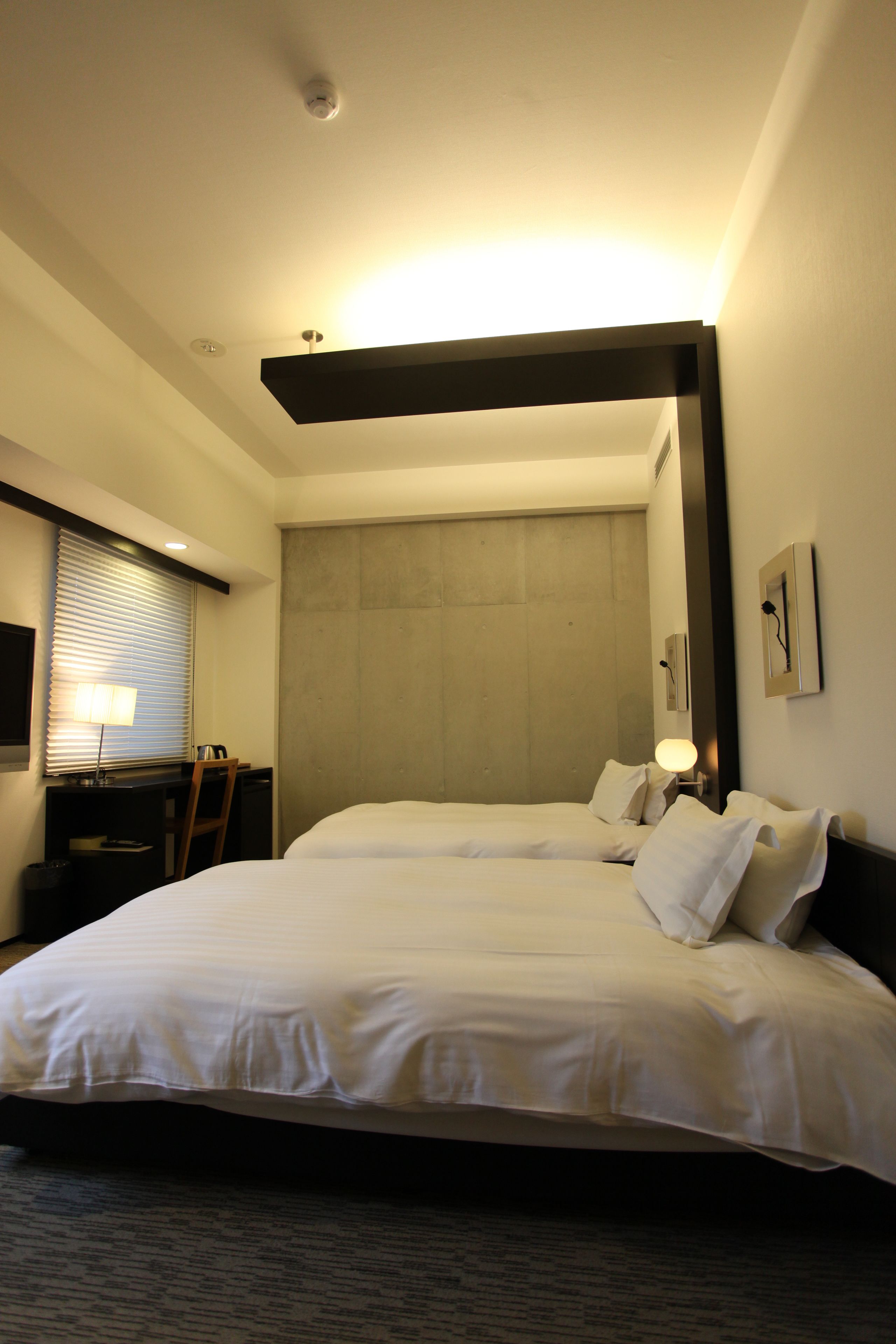 A hotel room with two beds, a desk, and a chair.