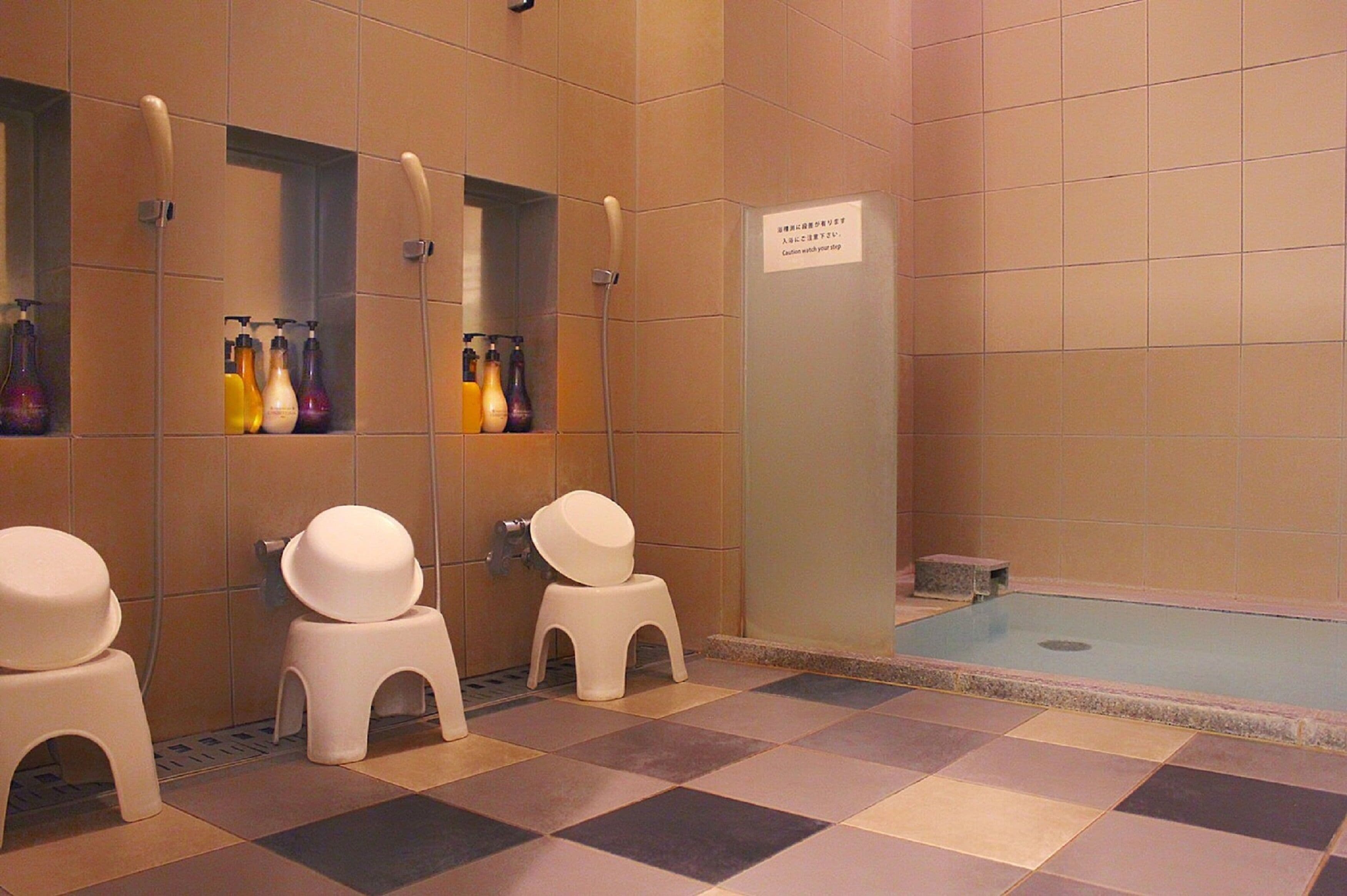 A bathroom with two toilets, a sink, and a shower area.