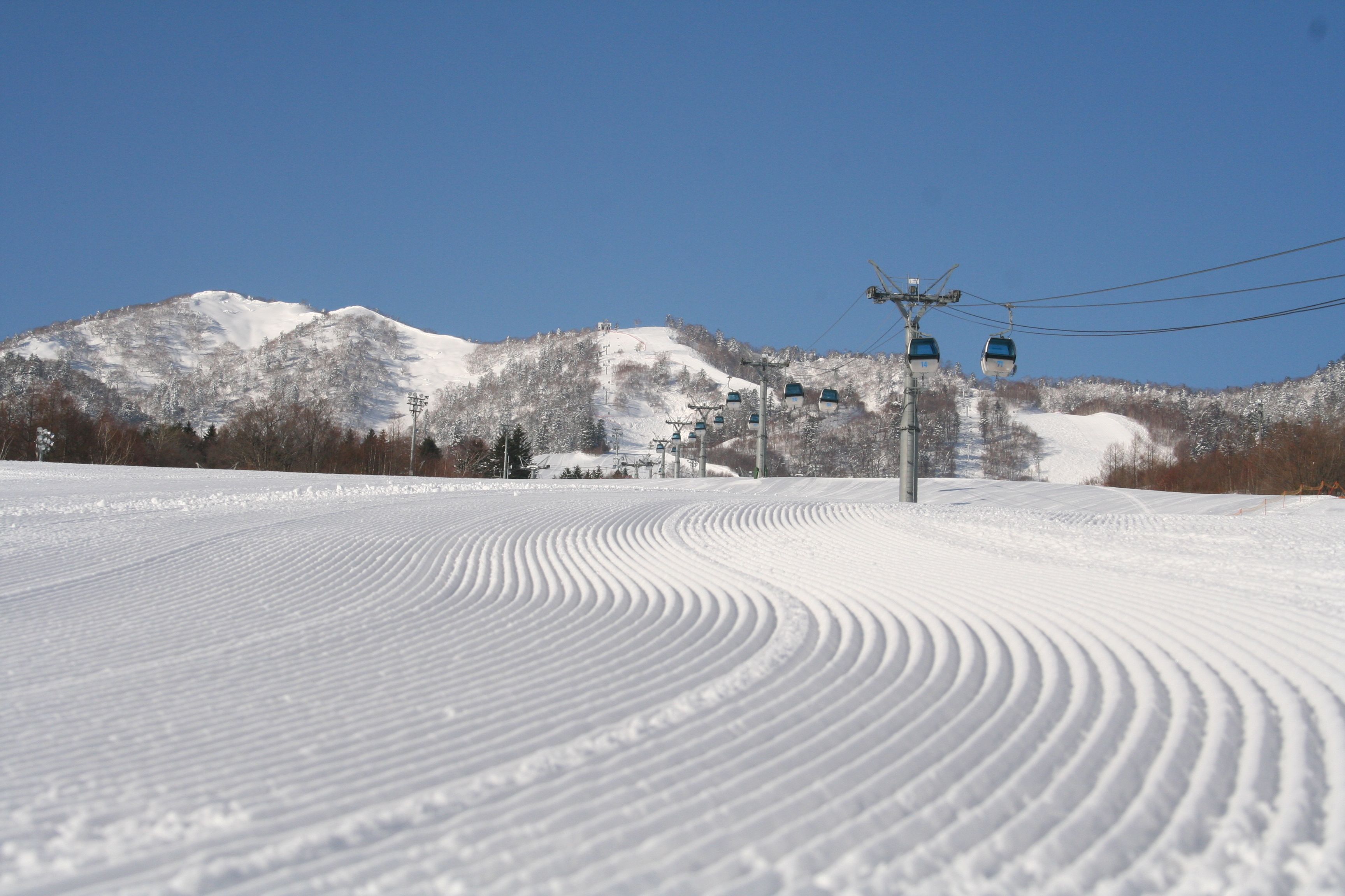Een pistes bedekt met sneeuw, met skiliften en een berg op de achtergrond.