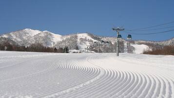 Pista de esquí nevada con telesillas y una montaña al fondo.