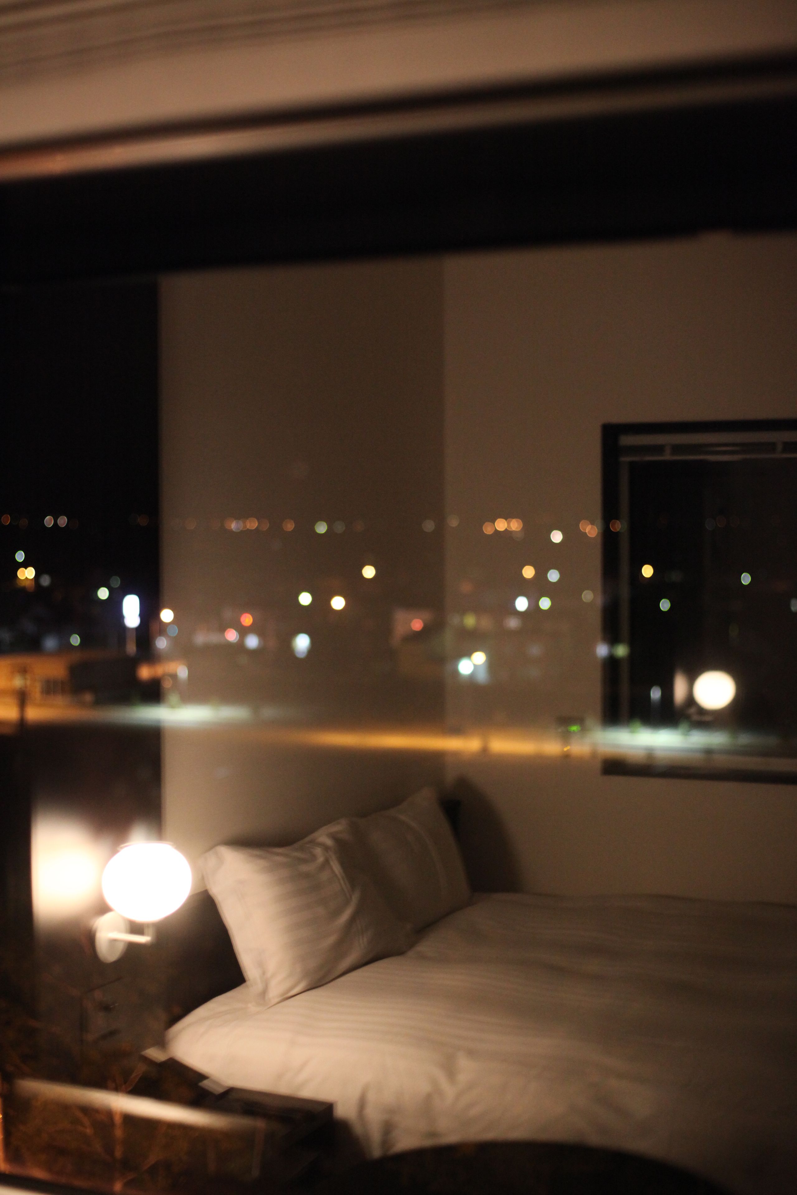 A bedroom with a bed, a nightstand, and a wall-mounted lamp.