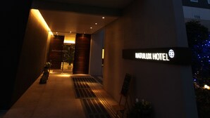 The exterior of the Natulux Hotel with a modern design, featuring a prominent sign and a well-lit entrance.